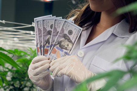 197431232-closeup-female-scientist-holding-dollar-banknotes-money-after-gratifying-profiting-from-selling